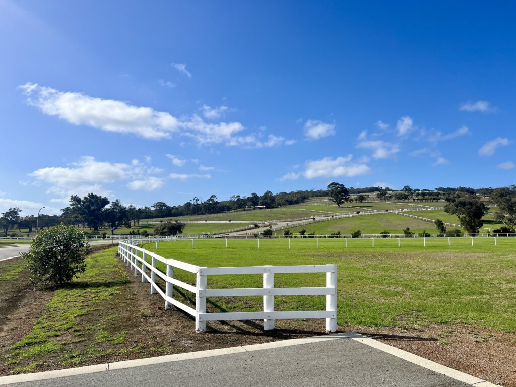 Green grass fields and white picket fence